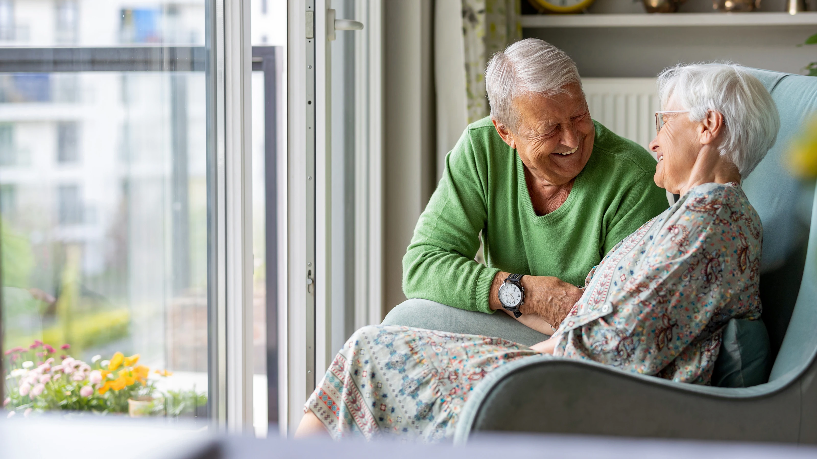 Man and woman smiling next to window