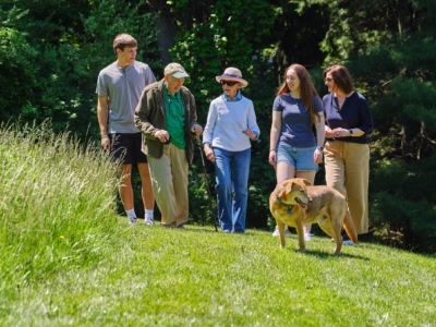 Family with dog walking on outdoor grass path