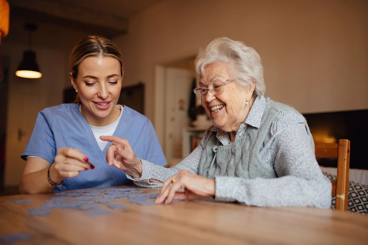 Resident and care giver working on a puzzle