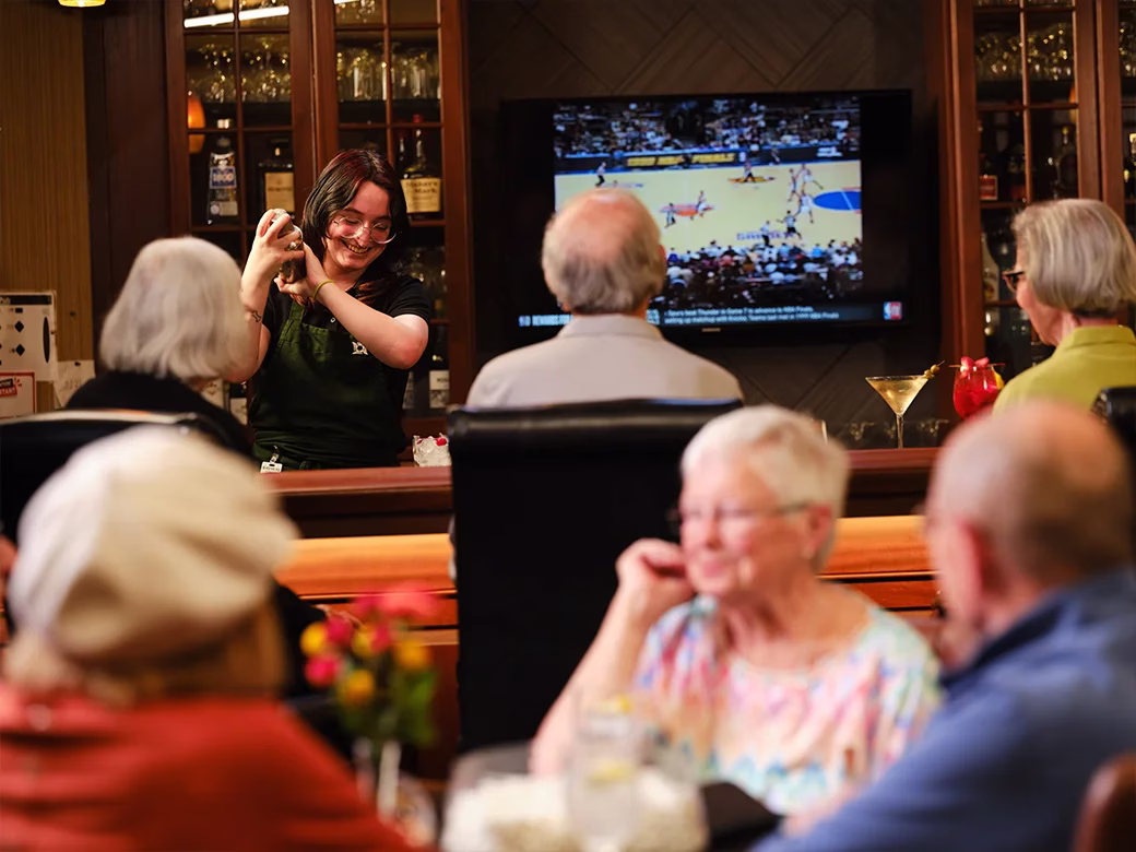 Server preparing drinks while residents watch sports