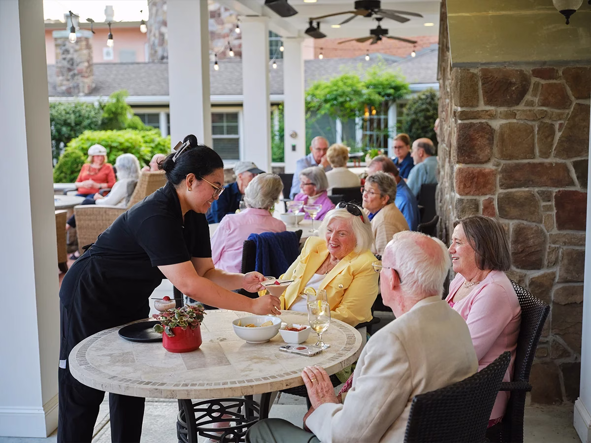 Server giving guests drinks on outdoor patio