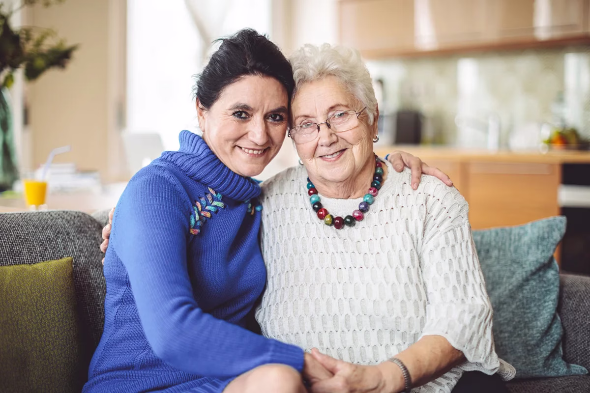 Resident and daughter on couch smiling