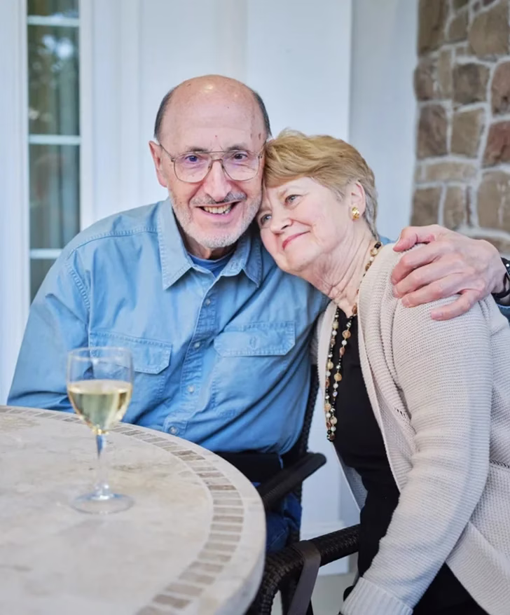 Man and woman embracing while sitting out side at a table